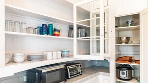 Una cocina con armarios blancos, microondas, horno tostador y diferentes utensilios de cocina.