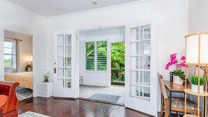 Una habitación con cama, escritorio y silla. Se ve vegetación por la ventana.