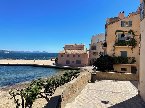 Un bâtiment situé sur la côte, doté d’un toit recouvert de tuiles, d’une allée pavée et offrant une vue sur la mer.