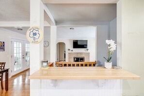 A modern kitchen with a wooden countertop, a white bench, a fireplace, and a clock on the wall. - Perfect ND Weekend Space <> 10 Min Walk to Campus (South Bend)