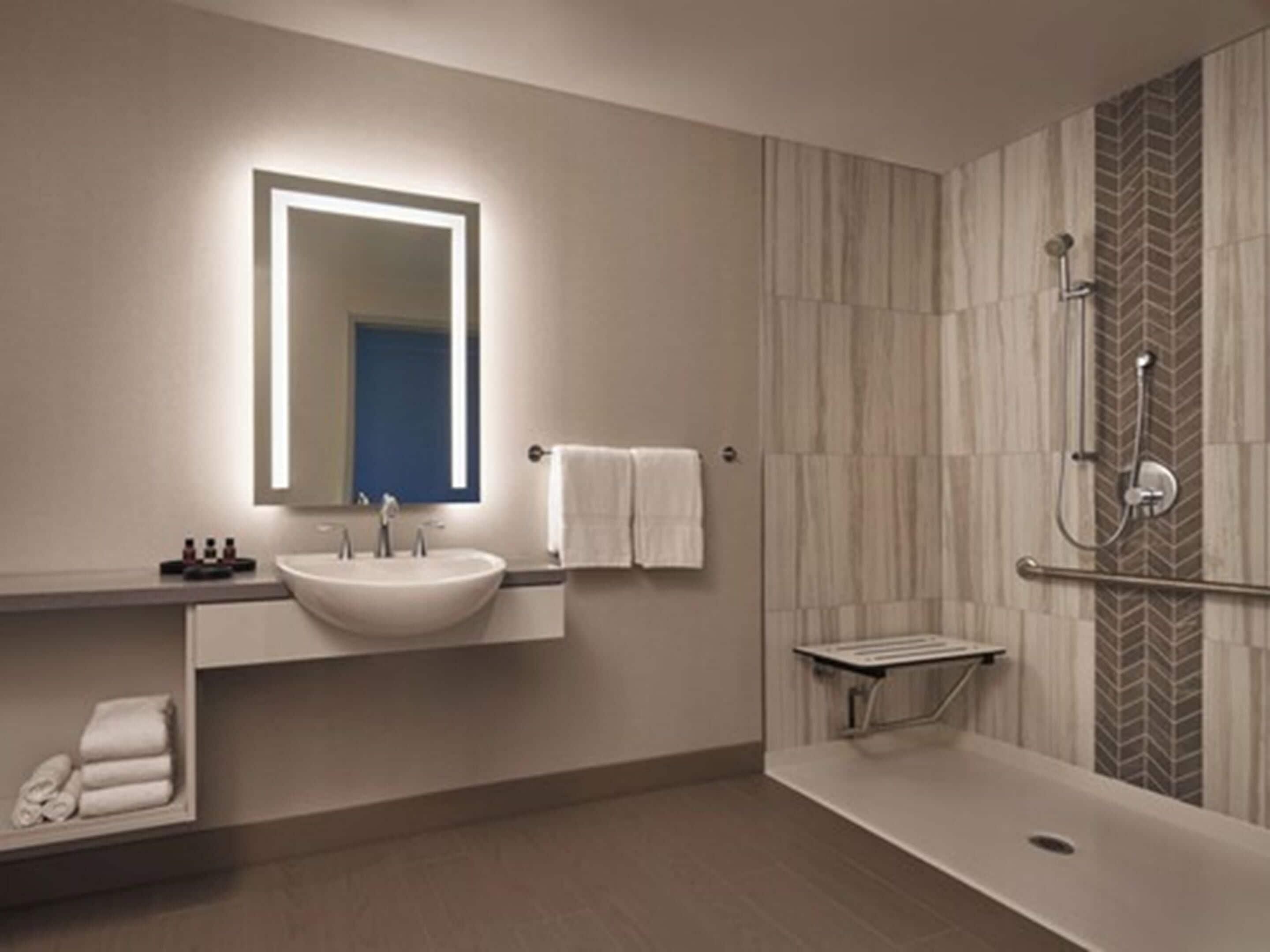 Un baño moderno con un lavamanos grande, un espejo, toallero y zona de ducha.