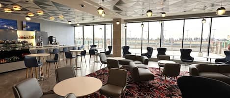 Un espace lounge moderne doté d’un bar, de sièges et de grandes fenêtres offrant une vue panoramique.
