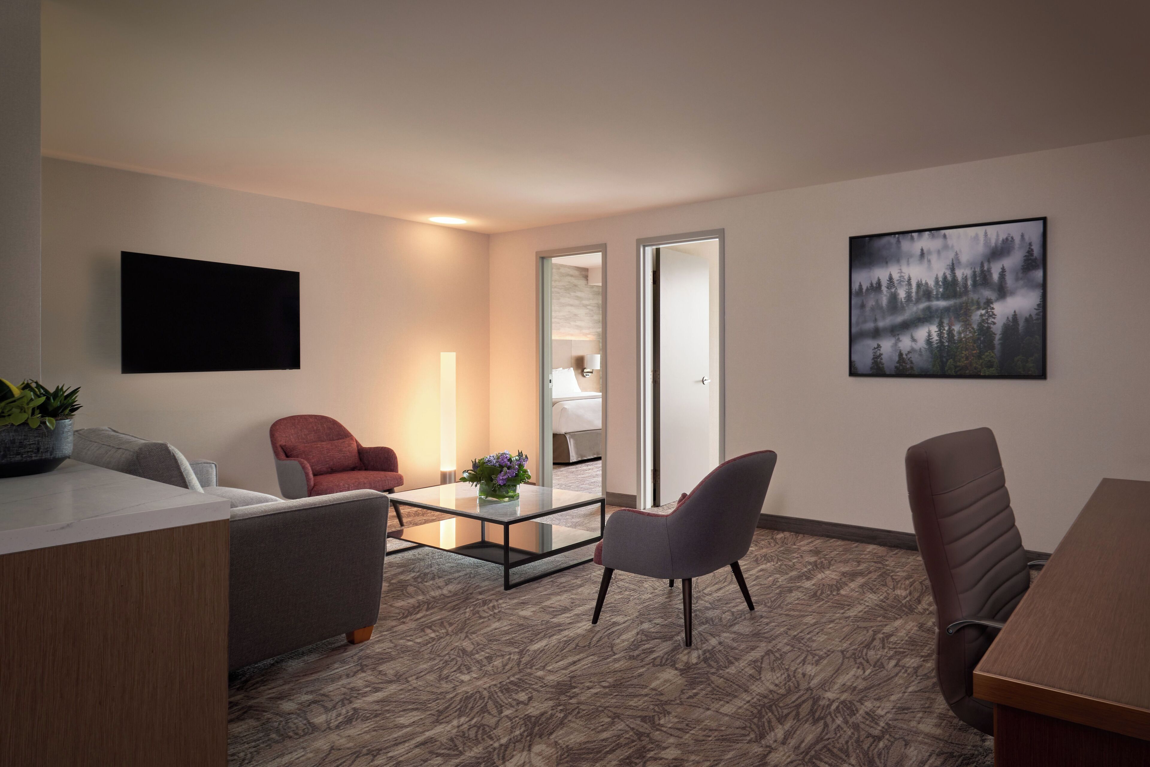 Een moderne hotelkamer met een flatscreen televisie, een bank, een bureau en een salontafel.