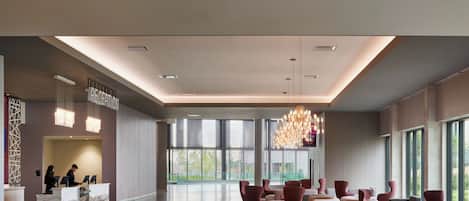 A modern lobby with a reception desk, seating area, and large windows.