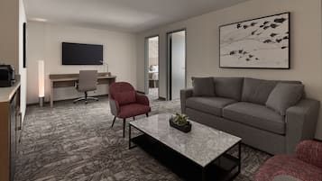 A modern living room with a grey sofa, a red armchair, a coffee table, a flat-screen TV, and a desk with a chair.
