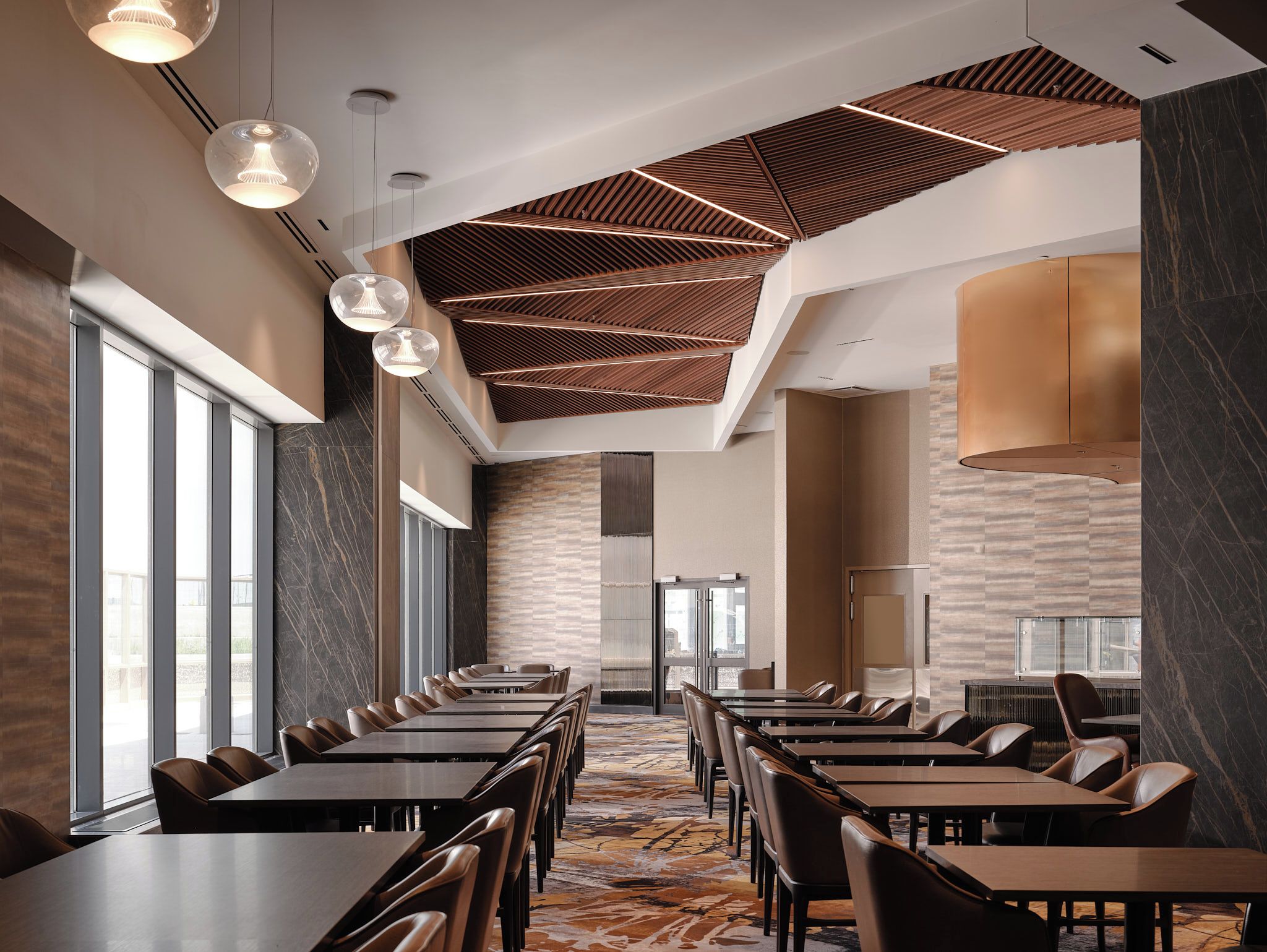 A modern hotel conference room with long tables, leather chairs, and a patterned carpet.