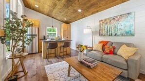 A modern kitchen with wooden cabinets, a stainless steel refrigerator, and a bar area with stools. - Dream Big in this new Tiny Home! Hot tub, firepit (Mineral Bluff)