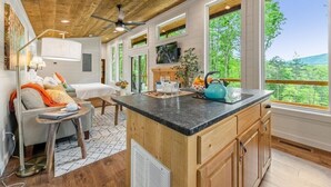 A modern kitchen with a wooden ceiling, large windows, and a central island. - Dream Big in this new Tiny Home! Hot tub, firepit (Mineral Bluff)