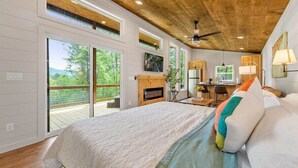 A bedroom with a large bed, a ceiling fan, and a view of the outdoors through sliding glass doors. - Dream Big in this new Tiny Home! Hot tub, firepit (Mineral Bluff)