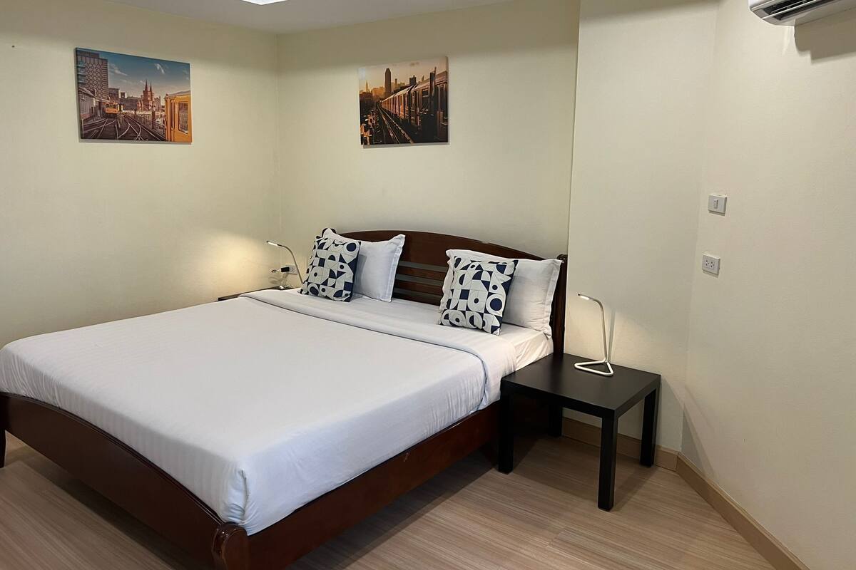 A neatly arranged bedroom with a large bed, two bedside tables, and two wall-mounted air conditioning units.