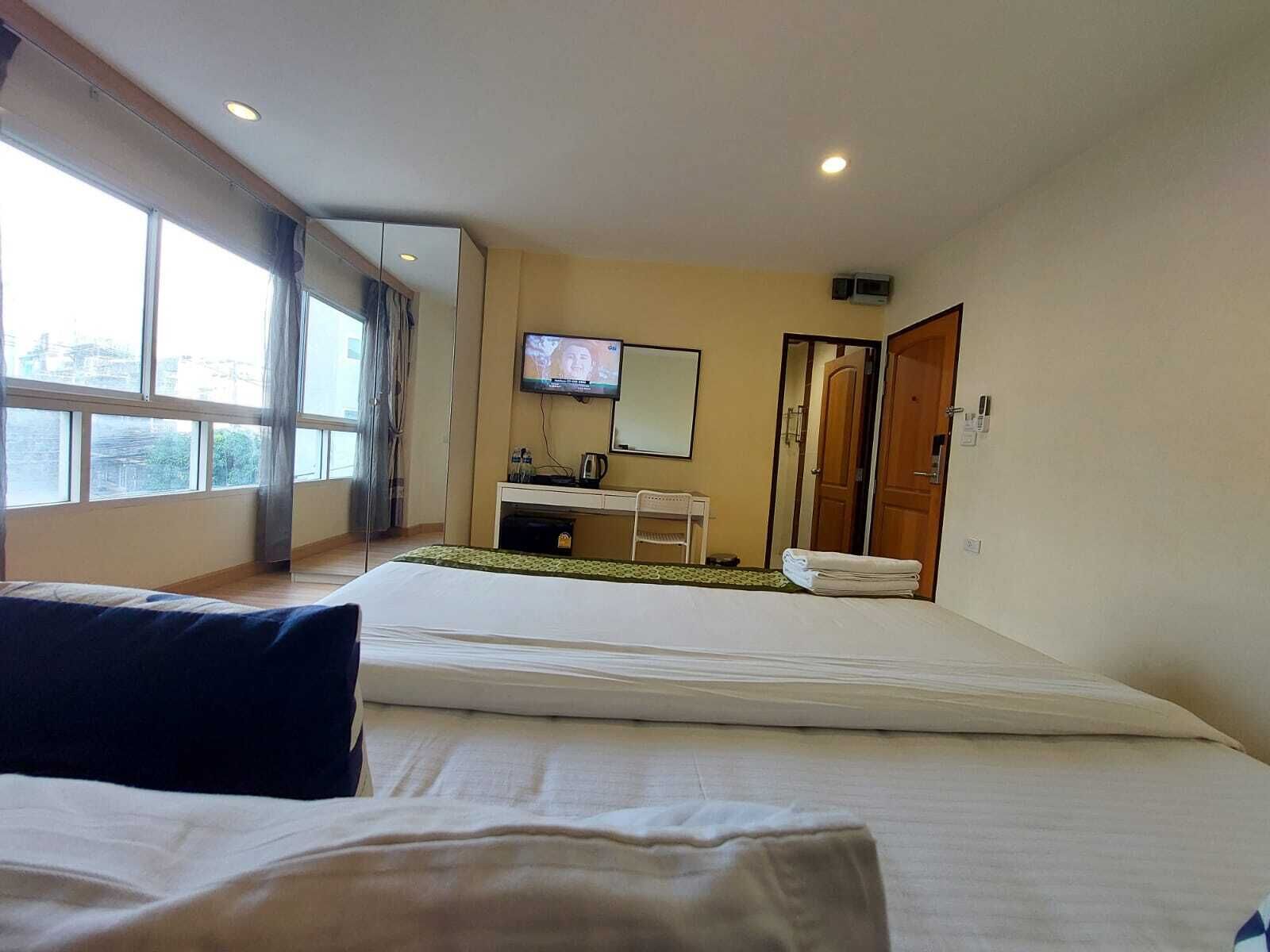Une chambre d’hôtel avec un lit, un bureau et une chaise, une télévision et une porte de salle de bain.