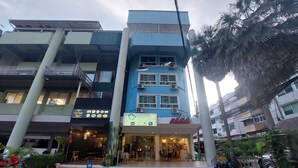 A multi-story building with a blue facade, a restaurant on the ground floor, and a parking area in front. - V Check Inn Sukhumvit 22 (Bangkok)