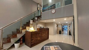 A hotel lobby with a reception desk, a staircase, and a dining area with a menu. - V Check Inn Sukhumvit 22 (Bangkok)