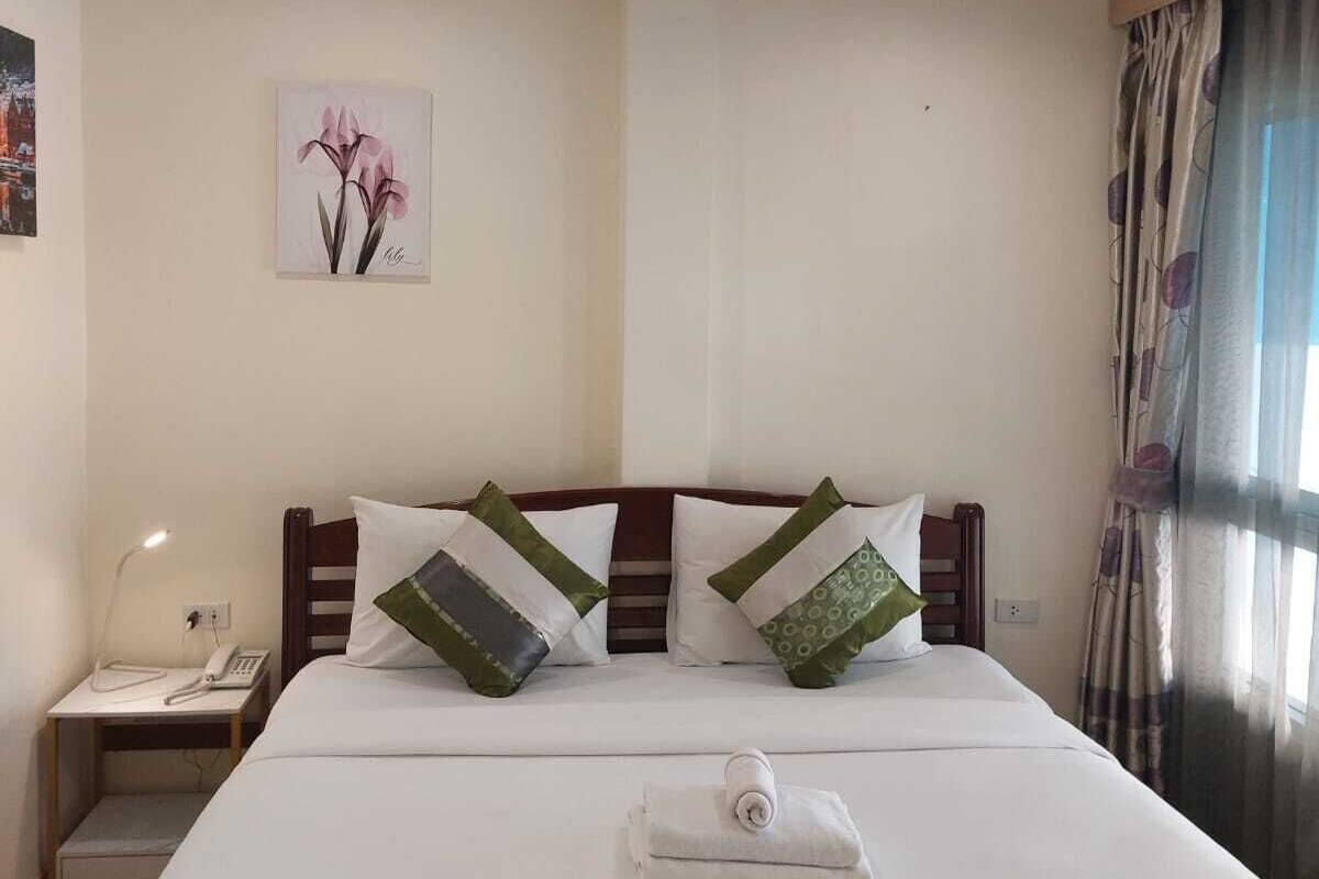 A hotel room with a large bed, two pillows, a bedside table with a lamp, and a painting on the wall.