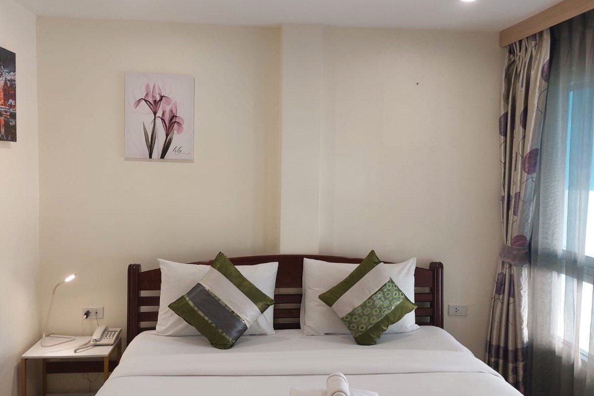 Une chambre d’hôtel avec un grand lit, deux oreillers, une table de chevet avec une lampe et un tableau au mur.
