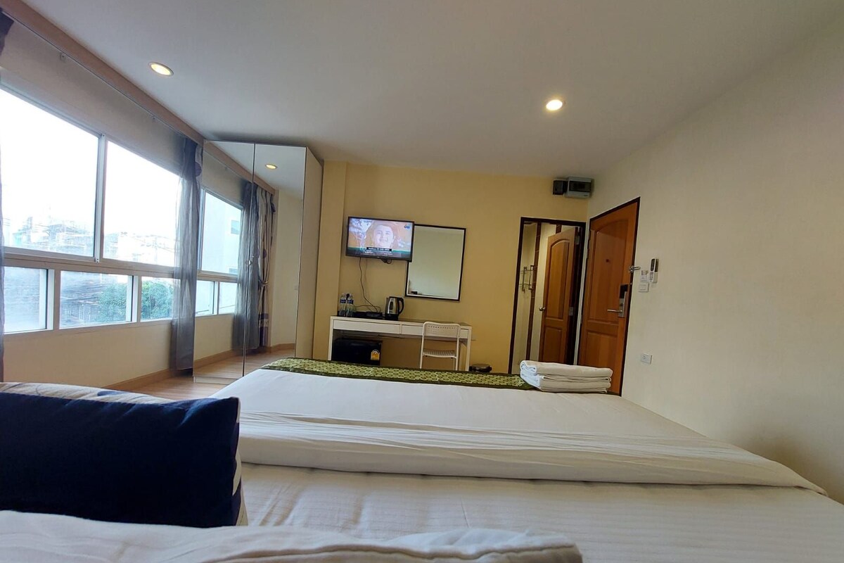 A hotel room with a bed, a desk with a chair, a television, and a bathroom door.