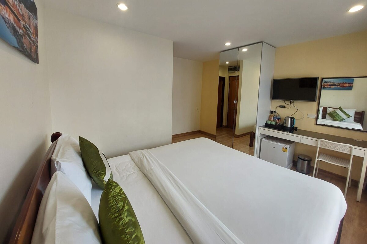 Una camera d'albergo con un letto, una scrivania, uno specchio e un televisore.