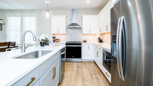 Une cuisine moderne avec des armoires blanches, des appareils en acier inoxydable et un plancher en bois.