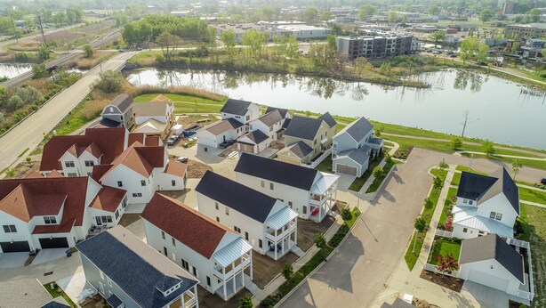 Un quartier résidentiel avec des maisons, un lac et un pont.