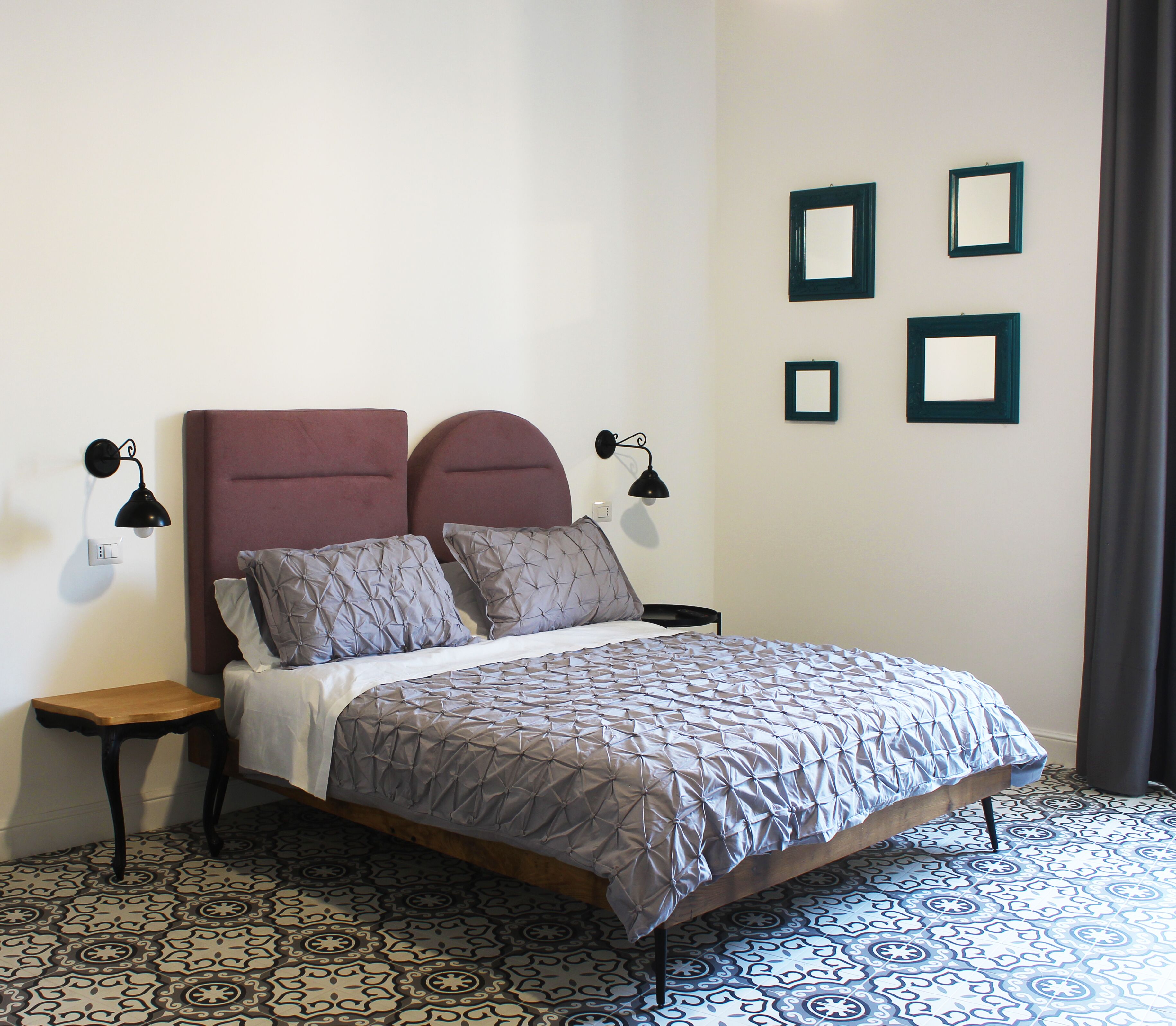 A neatly made bed with a patterned bedspread, two bedside lamps, and a small wooden nightstand.