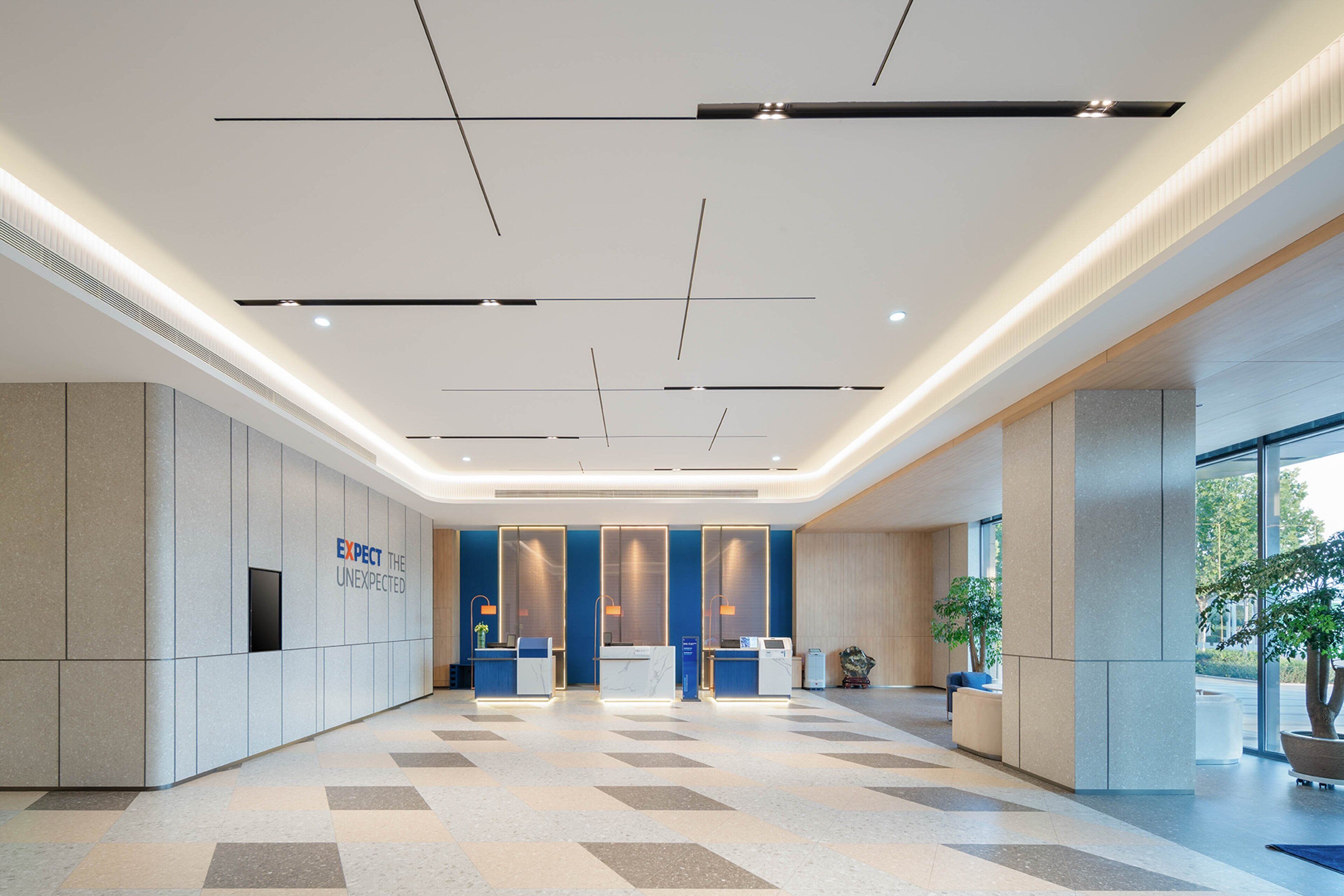 A spacious lobby with a modern design, featuring a reception desk, seating area, and large windows allowing natural light.