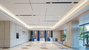 A spacious lobby with a modern design, featuring a reception desk, seating area, and large windows allowing natural light.