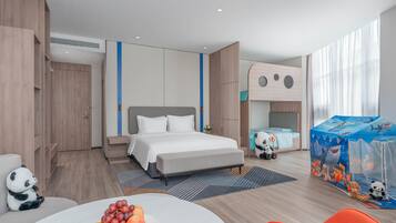 Ein modernes Hotelzimmer mit Bett, Schreibtisch und einer Essecke mit Obst.