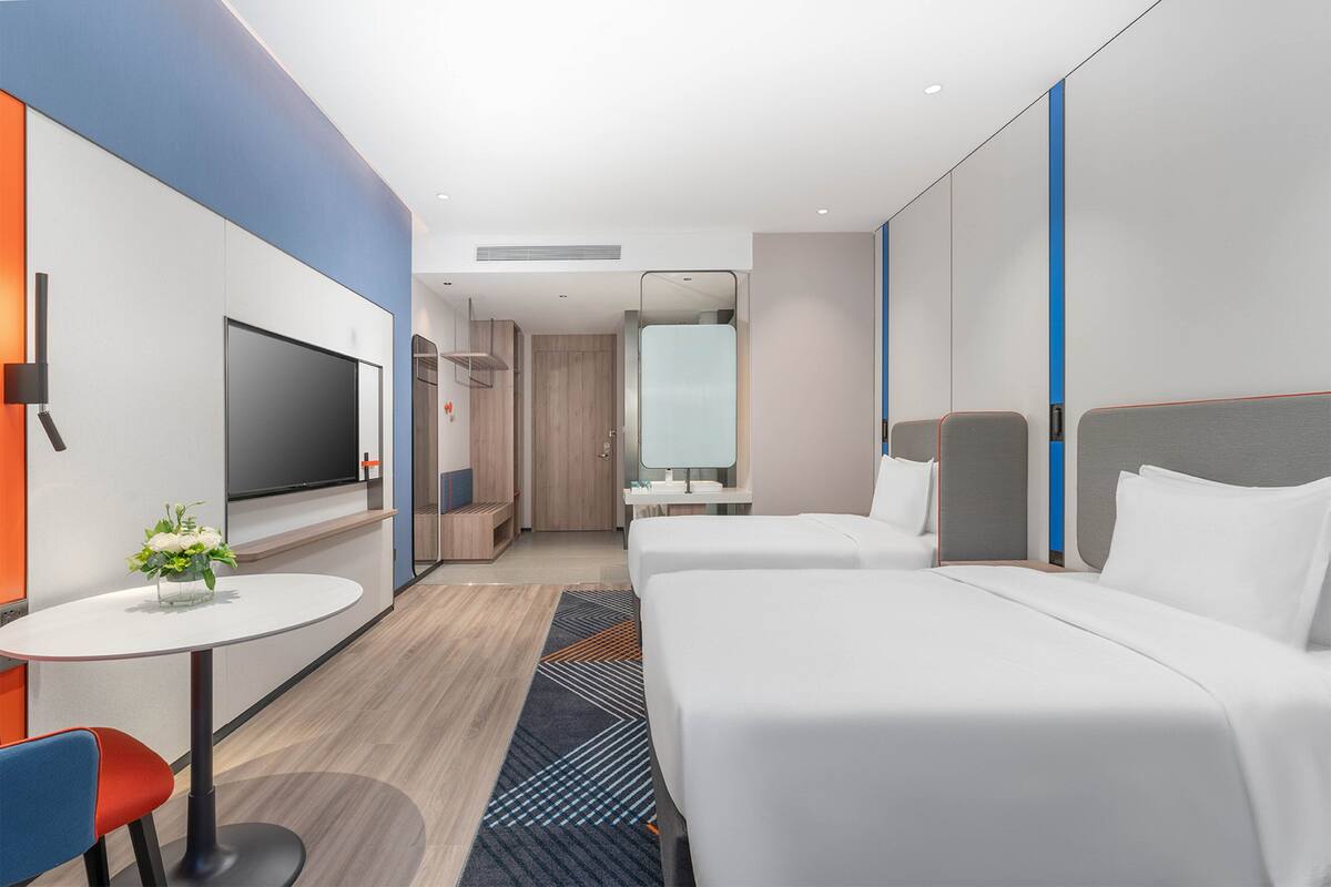 Une chambre d’hôtel moderne équipée d’une télévision, de deux lits, d’une petite table et d’un coin salon.