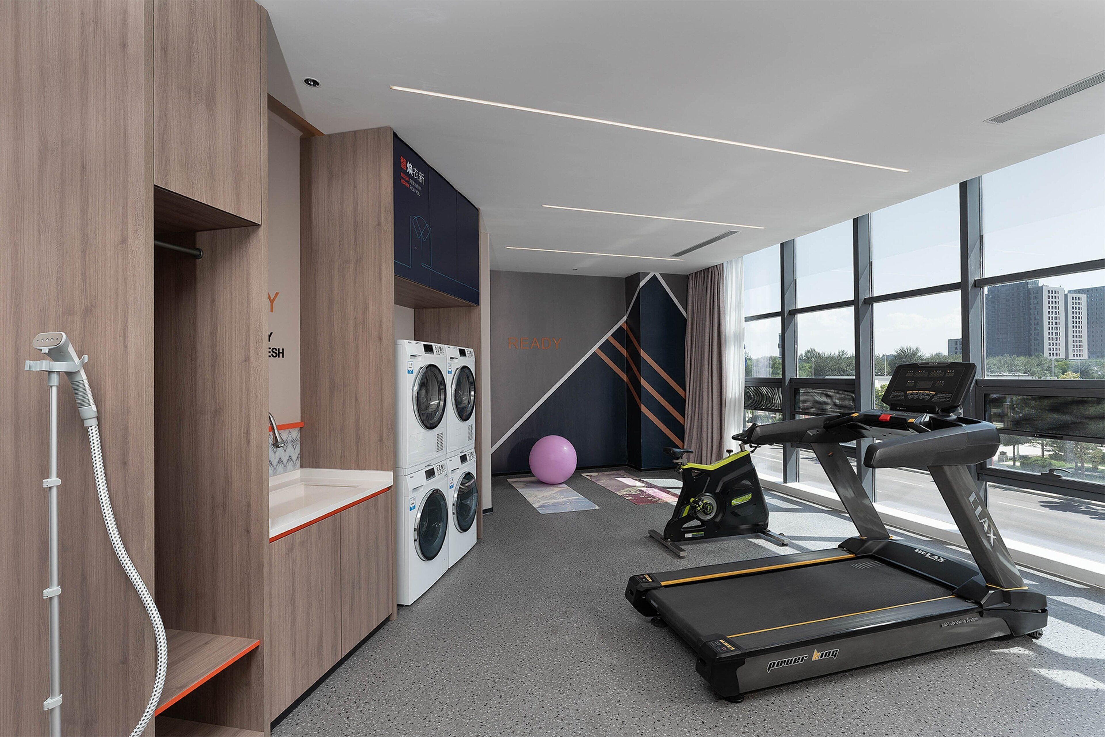 A modern gym with a treadmill, stationary bike, and washing machines.