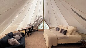 A cozy tent interior with a bed, sofa, and table. - Teton View Tent (Tetonia)