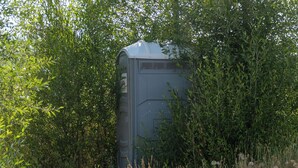 A portable toilet in a wooded area. - Teton View Tent (Tetonia)
