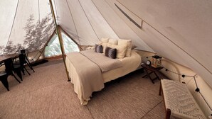 A cozy tent with a bed, a small table, a chair, and a lamp. - Teton View Tent (Tetonia)