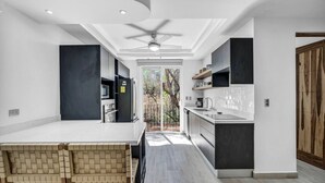 A modern kitchen with a central island, built-in appliances, and a view to the outdoors. - Gav4: New Condo in Location Walkable to Beach (Tamarindo)