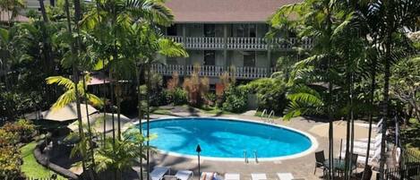 Zona de piscina con sillas de descanso y un edificio al fondo.