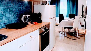 Cuina compacta amb microones, cafetera i nevereta. Zona de menjador amb taula i cadires.