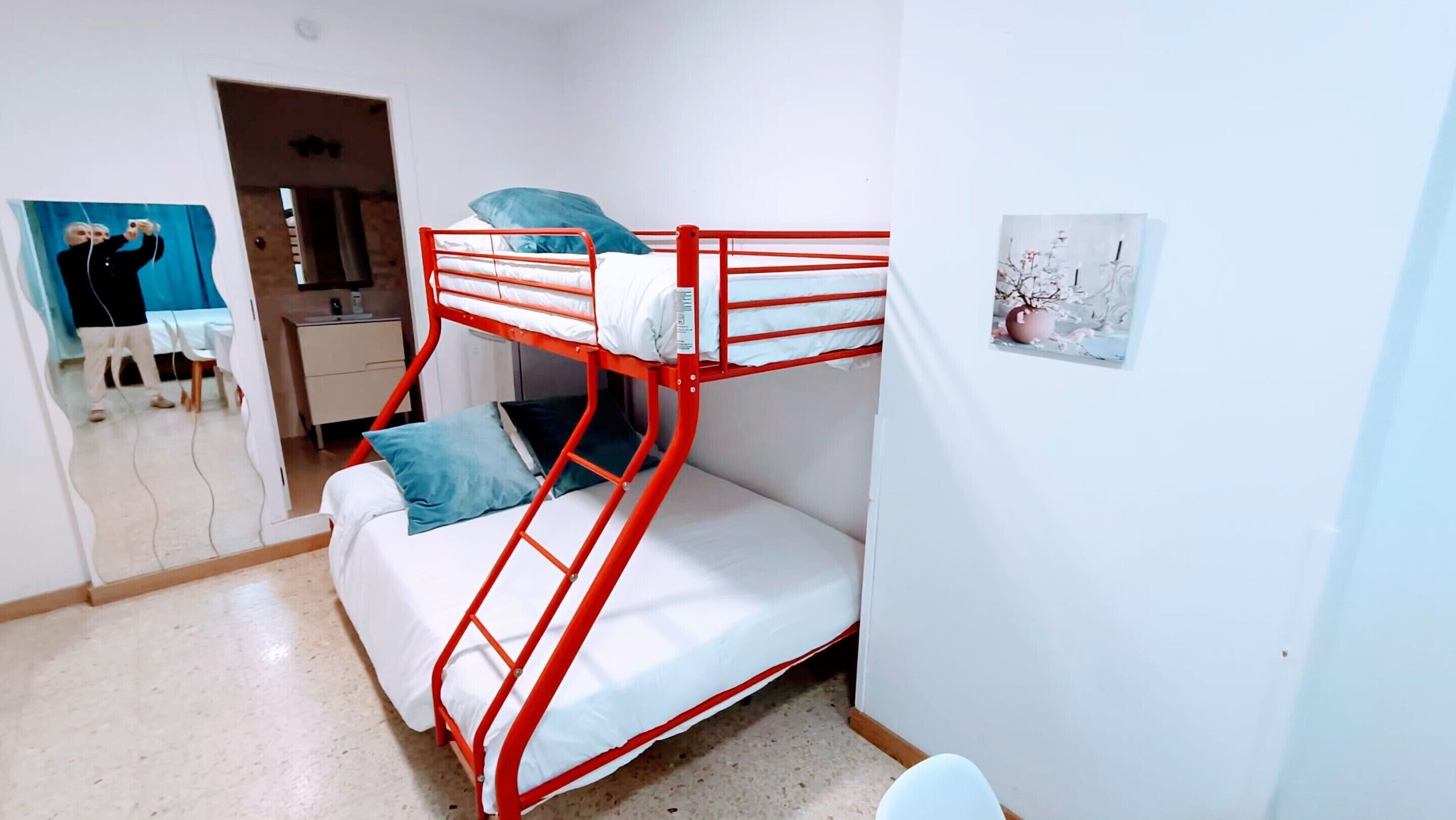 Habitación con literas, un espejo, una mesita pequeña y un armario.