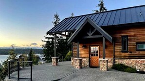 A log cabin with a stone foundation, a metal roof, and a wooden door. - Private beach luxury home sleeps 12, Shelton, WA (Shelton)