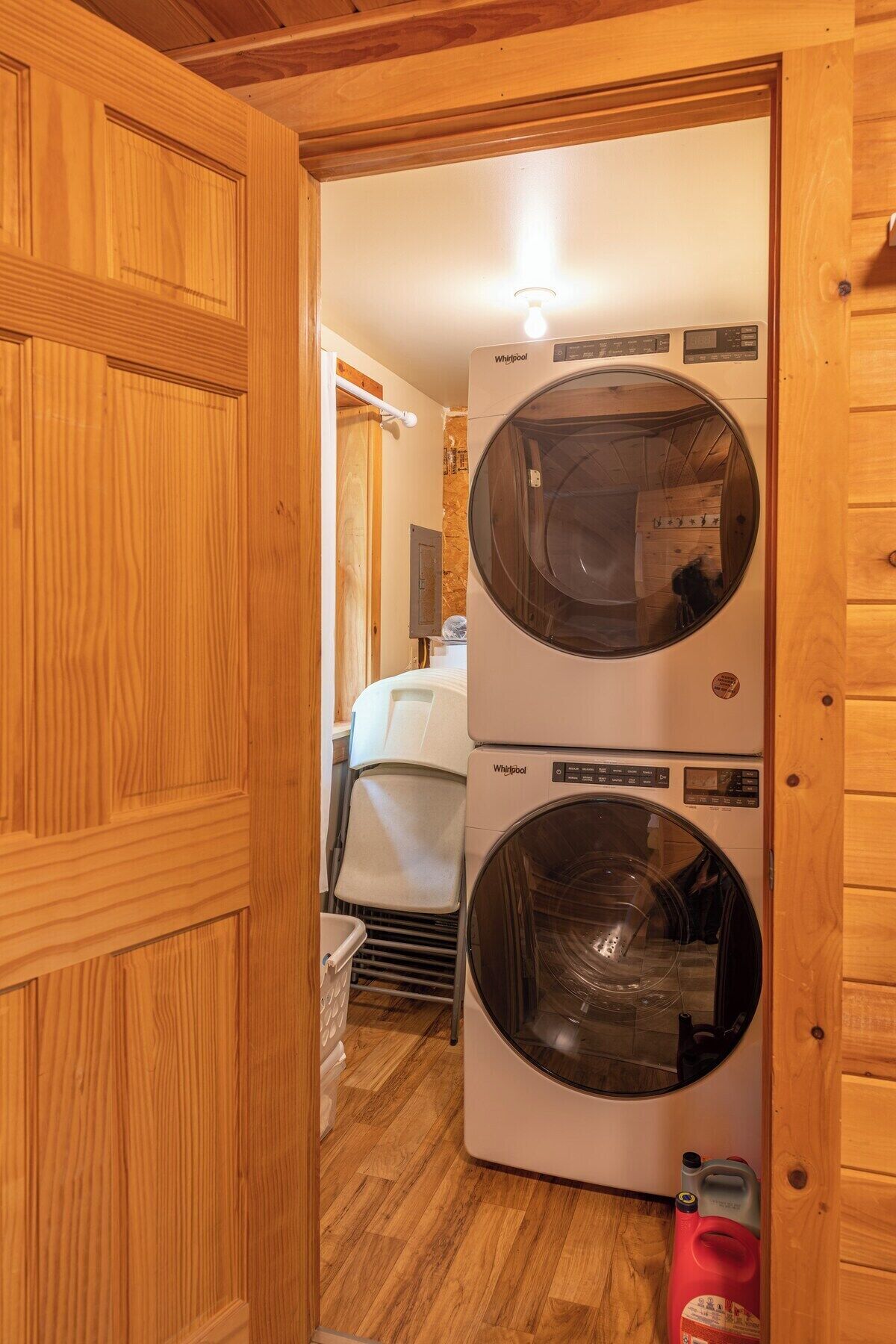 Ett tvättrum med två tvättmaskiner från Whirlpool, träväggar och ett trägolv.