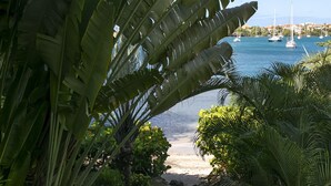 A view of a beach with boats in the water, surrounded by lush greenery. - luxury Two Bedroom Private Home/ your ideal way to vacation (St george)