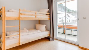Een slaapkamer met stapelbedden, een groot raam en uitzicht op een besneeerd landschap.