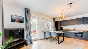 Een moderne keuken met grijze kastjes, een inbouwoven en een eethoek met een tafel en stoelen.