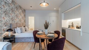 Ein modernes Hotelzimmer mit einem Bett, einem Esstisch für zwei Personen und einer Küchenzeile.