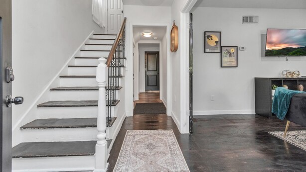 A staircase leading to a landing with a dark wood floor, a white door, and a black console with a teal throw.