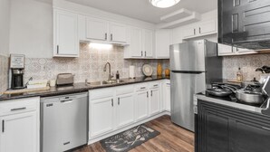 A modern kitchen with white cabinetry, stainless steel appliances, and a patterned backsplash.
