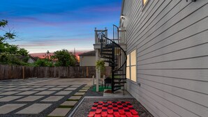 A backyard with a checkered floor, a spiral staircase, and a wooden fence.
