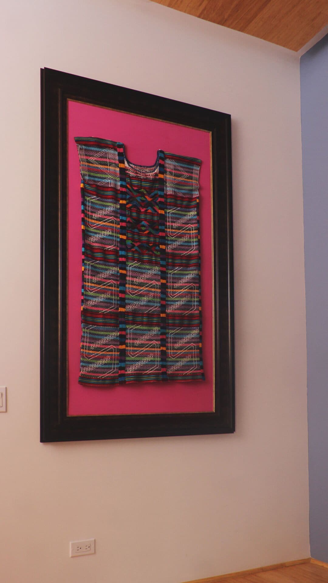 Une œuvre d’art textile encadrée, accrochée au mur.