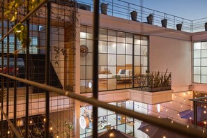 A modern hotel with a spacious lobby, a rooftop terrace with plants, and a visible restaurant area.