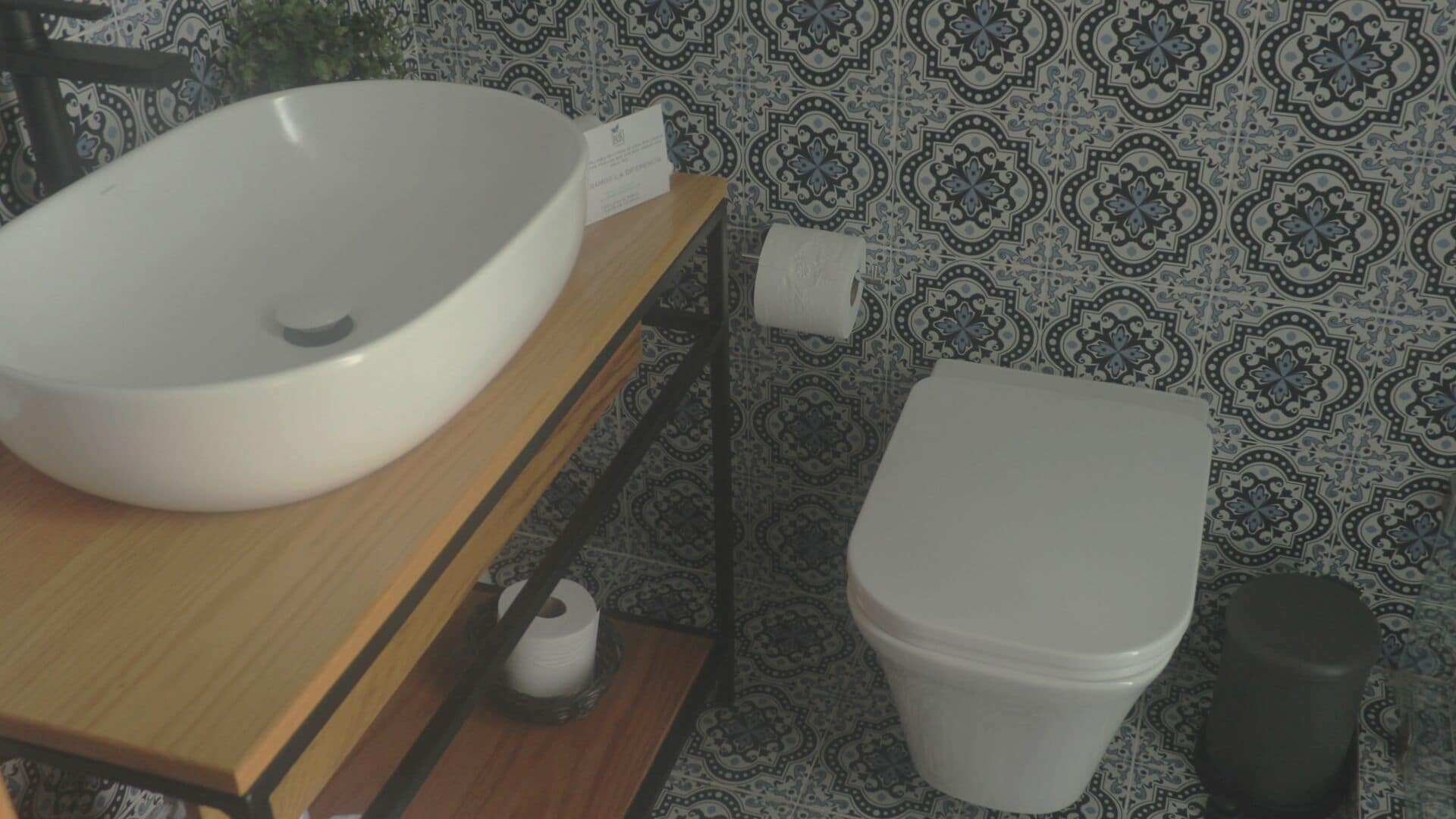 Un bagno con un lavandino bianco, un water e un rotolo di carta igienica su un ripiano in legno.