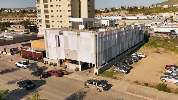 A multi-story building with a parking lot in front. - Hotel Brecha (Tijuana)