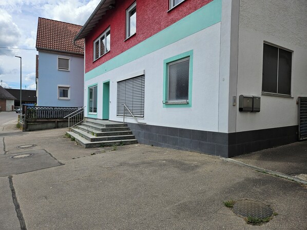 A building with a red and white facade, a staircase leading to the entrance, and a metal gate.